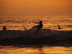 Surfistas na praia de Kuta ao entardecer